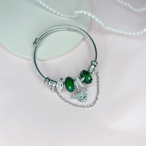 Silver steel bracelet featuring green crystals, a heart charm, and a 3D crown pendant