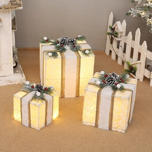 Three-piece glowing Christmas gift boxes set with gold ribbons and warm LED lights