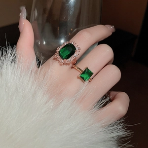Detailed close-up of emerald-cut gemstone rings with diamond halo on rose gold bands