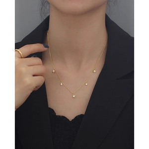 Detail of gold S925 silver necklace featuring star charms and clear gemstones on model