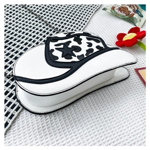 Detail of white cowhide print cowboy hat crossbody bag with star and chain strap
