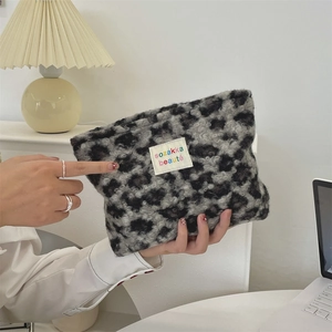 Detail of leopard print plush cosmetic bag showing soft faux fur texture and woven label