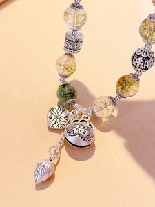 Macro shot of ethnic crystal beaded bracelet featuring silver Fu character and bell pendants