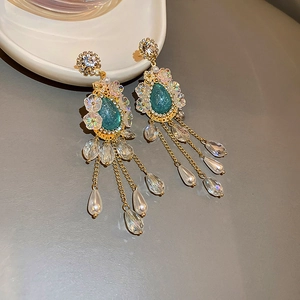 Macro detail of vintage gold fringe earrings with teal gems, crystals and faux pearls