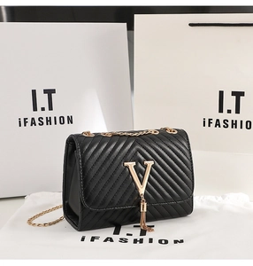 Detail of black V-quilted chain bag with gold tassel and elegant hardware finish