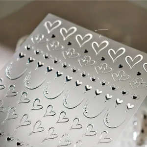 Macro shot of 3D metallic silver heart nail art stickers with embossed hollow patterns