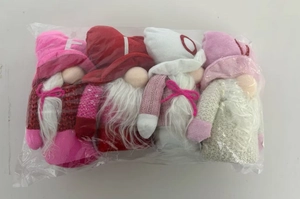 Detail view of four plush Valentine gnomes in pink and red tones inside packaging