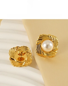 Detailed close-up of baroque pearl stud earrings with golden spiral square metal base