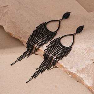 Macro shot of dark gothic tassel earrings with black rhinestones on natural stone background