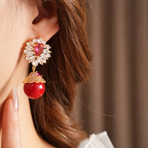 Détail de boucles d'oreilles vintage avec gouttes rouges, dorure et zircons sur mannequin