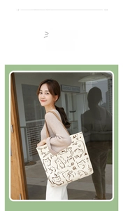 Detail of beige canvas tote bag featuring brown cat illustrations and wide shoulder straps
