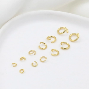 Macro shot of 14K gold-plated jump rings in various sizes on a white ceramic tray