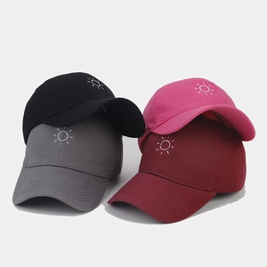 Detail view of four-color cotton baseball caps with embroidered sun icons and stitching
