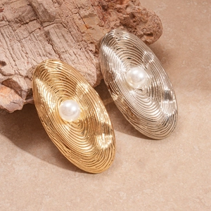 Textured gold and silver oval open rings with faux pearls on a natural rock background