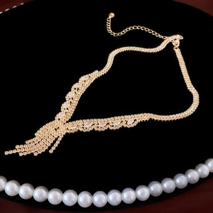 Macro detail of gold tassel rhinestone necklace with adjustable chain on black velvet