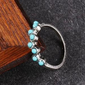 Gros plan d'une bague en argent vintage avec sept pierres turquoise sur fond de pierre
