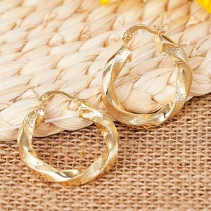 Detailansicht goldener gedrehter Creolen mit polierten und mattierten Oberflächen