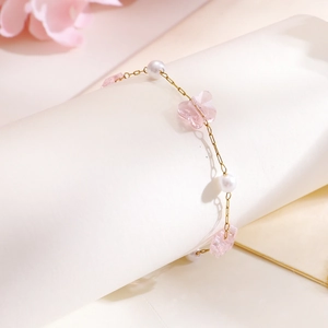 Macro view of gold children's bracelet with pink butterflies and pearls on white background