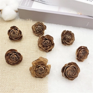 Close-up of natural dried cedar rose pine cones on soft white fur and rustic linen fabric