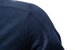 Macro detail of navy blue jacket shoulder showing flatlock seam and textured knit fabric