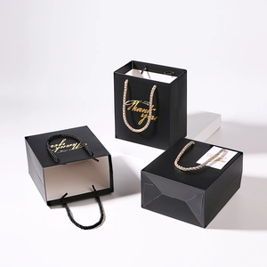 Elegant black paper gift bag with golden Thank You print and woven handles for weddings