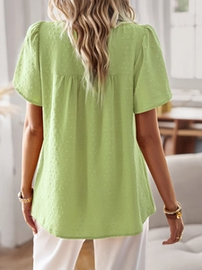 Back view of light green crew neck blouse showing delicate jacquard dot texture and pleats