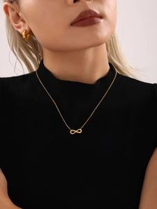 Détail macro du collier à trois rangs doré avec symbole infini et perles d'eau douce