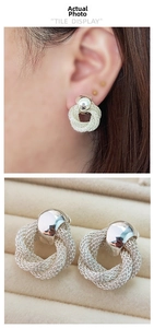 Detail view of woven twisted silver earrings worn and placed on a velvet box