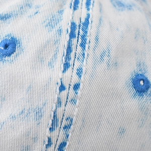 Detail einer blauen gewaschenen Denim-Baseballkappe mit weißen Nähten und Stickerei
