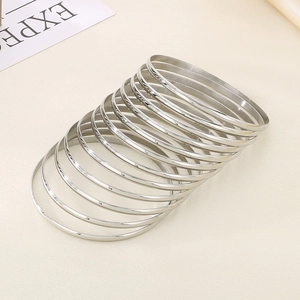 Close-up of polished 3.6mm silver stainless steel stackable bangles on a textured surface
