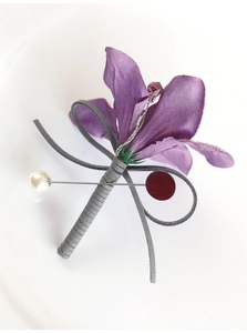 Detail view of handmade purple satin boutonniere with pearl pin for wedding suits