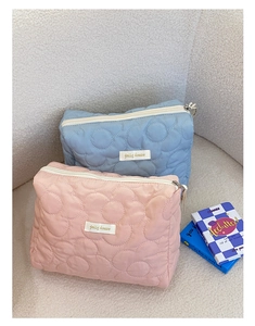 Gros plan de grandes trousses de maquillage matelassées à fleurs avec fermetures éclair