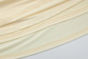 Detail of high-quality flatlock stitching and hem finish on yellow knitted dress fabric