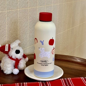Detail of cute puppy pattern and red apple print on a cream stainless steel bottle