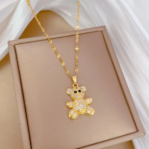 Detailed close-up of a golden teddy bear necklace pendant with crystals in a beige box