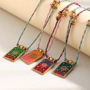 Detail of 18K gold tarot sun necklaces with colorful hand-woven cords and enamel pendants