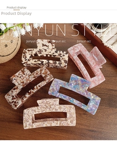 Detail shot of five large acetate hair claws in assorted vintage patterns on a wooden surface