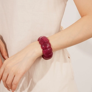Close-up of deep red acrylic stretch bracelet with marbled texture on woman's wrist