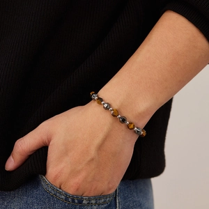 Close-up of beaded bracelet with tiger eye stones and black beads on a model's wrist