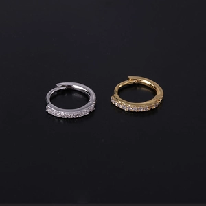 Macro shot of minimalist gold and silver mini huggie hoop earrings with paved cubic zirconia
