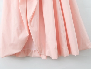 Detailed view of the pink ruffled hem with smooth fabric texture on this halter dress