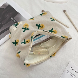 Trousse à maquillage en toile beige avec broderies florales et fermeture éclair en métal