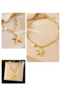 Detail view of gold starfish pendant with white pearl and premium gift packaging