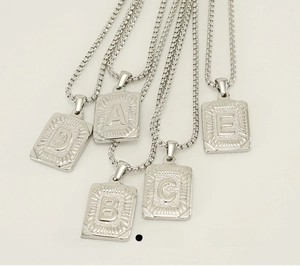 Macro view of polished stainless steel rectangular letter pendants on square link chains