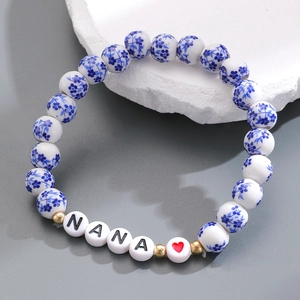 Dettaglio del bracciale in ceramica bianca e blu con lettere NANA e accenti dorati