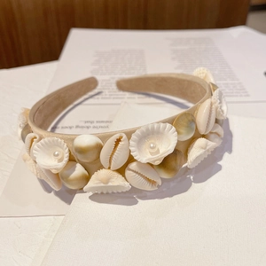 Detail of baroque headband with natural shells and pearls on a beige fabric base