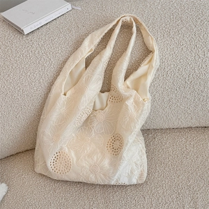 Close-up of the delicate floral embroidery and openwork texture on the beige lace tote bag