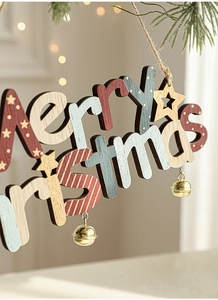 Detailed close-up of wooden Merry Christmas hanging sign with bells on a pine branch