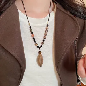 Vintage ethnic necklace with botanical beads and wooden pendant on professional model