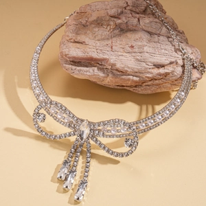 Elegant bowknot necklace with sparkling rhinestones and white pearls on light stone